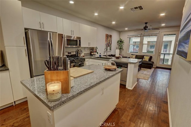 kitchen with dark wood finished floors, visible vents, appliances with stainless steel finishes, white cabinetry, and a peninsula