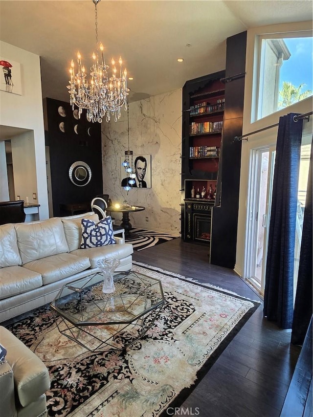 living area featuring a chandelier, an accent wall, and wood finished floors