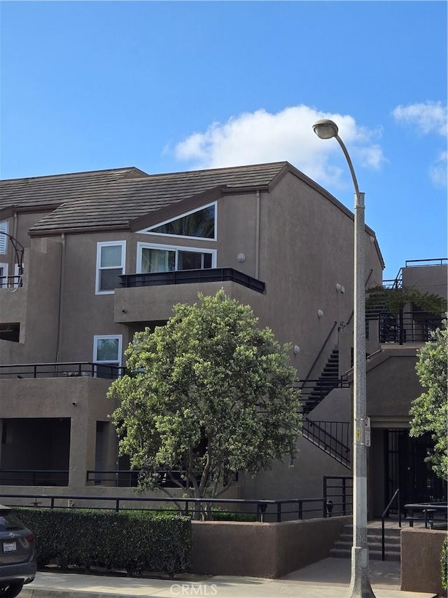 view of side of home with stairs and stucco siding