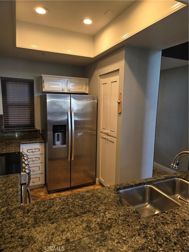 kitchen with dark stone counters, stainless steel appliances, white cabinetry, a sink, and recessed lighting