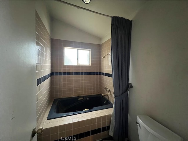 bathroom with tiled shower / bath, lofted ceiling, and toilet