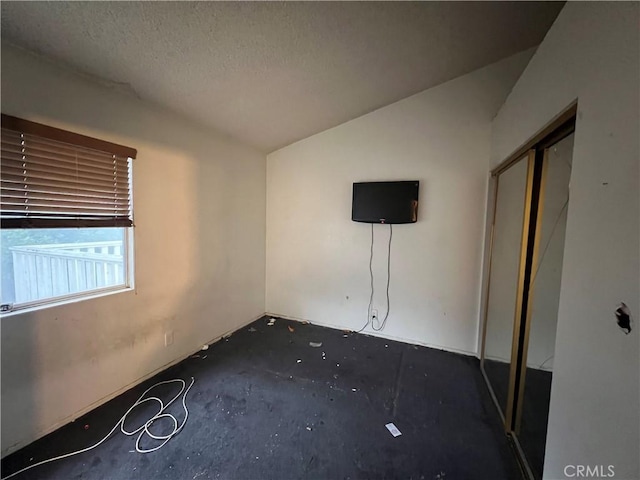 unfurnished bedroom with lofted ceiling and a textured ceiling