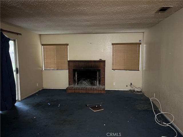 unfurnished living room with baseboards, a fireplace, visible vents, and a textured ceiling