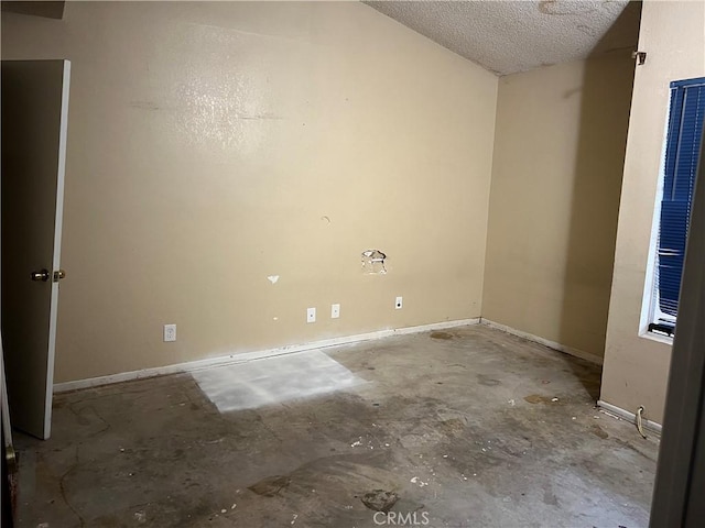 unfurnished room with baseboards, unfinished concrete flooring, and a textured ceiling