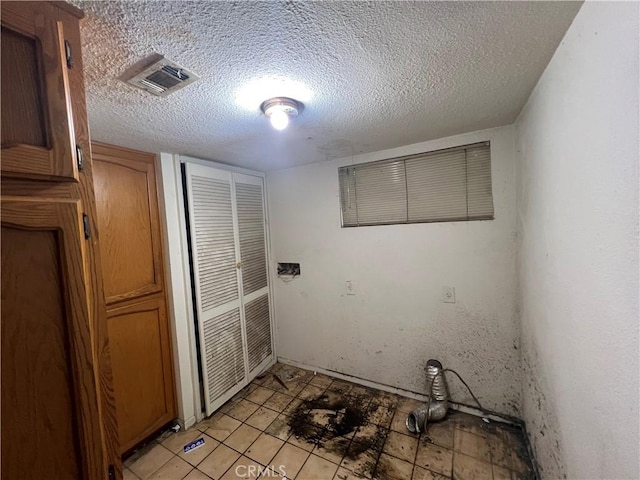 washroom with visible vents, a textured ceiling, and laundry area