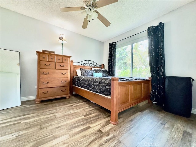 bedroom featuring a textured ceiling, ceiling fan, baseboards, and light wood-style floors