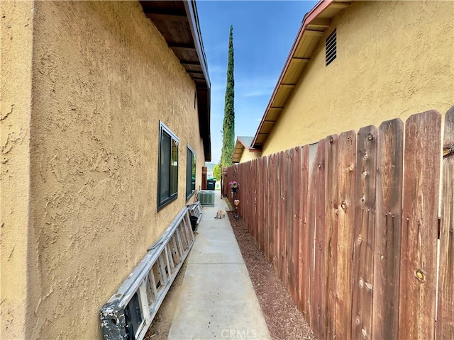 view of side of home with fence and stucco siding