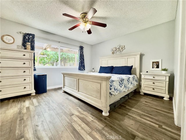 bedroom with dark wood-type flooring, ceiling fan, a textured ceiling, and baseboards