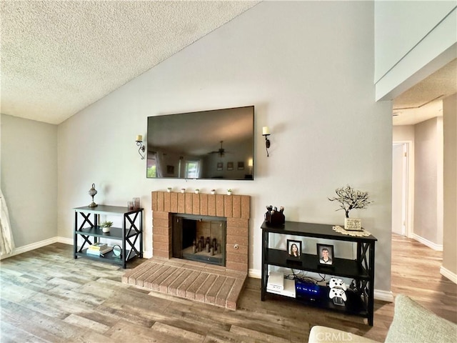 living room with a textured ceiling, a fireplace, wood finished floors, and baseboards