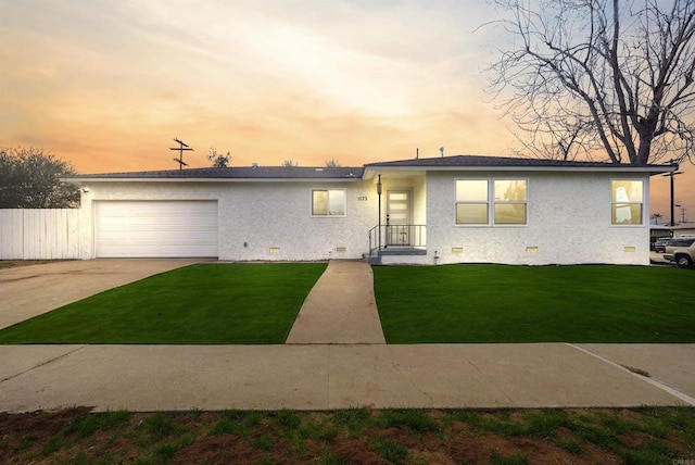 ranch-style house with crawl space, an attached garage, a lawn, and stucco siding