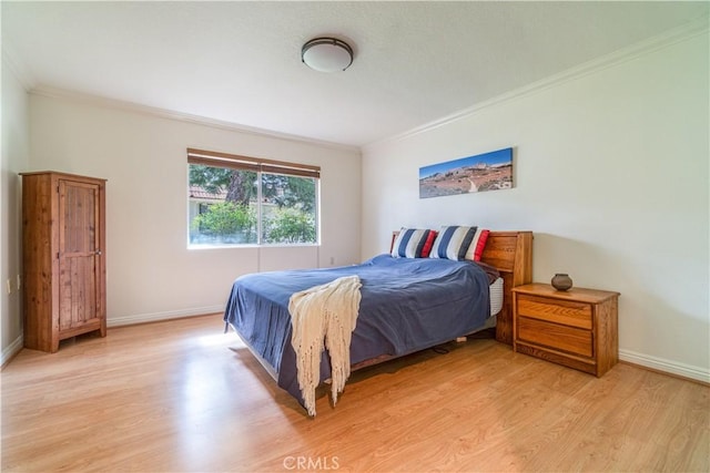 bedroom featuring light wood-style floors, crown molding, and baseboards