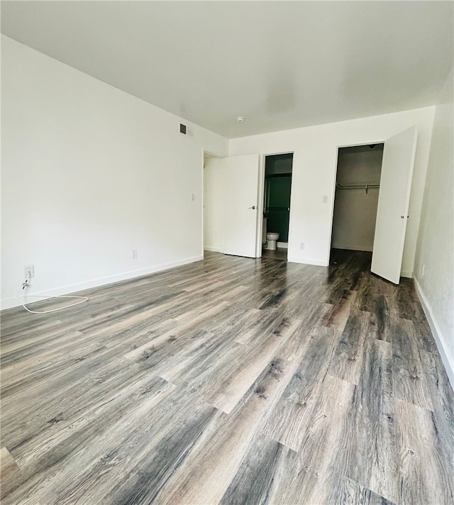 unfurnished bedroom with baseboards, a closet, visible vents, and wood finished floors