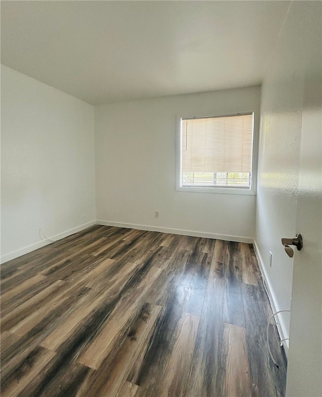 empty room featuring baseboards and dark wood-style flooring