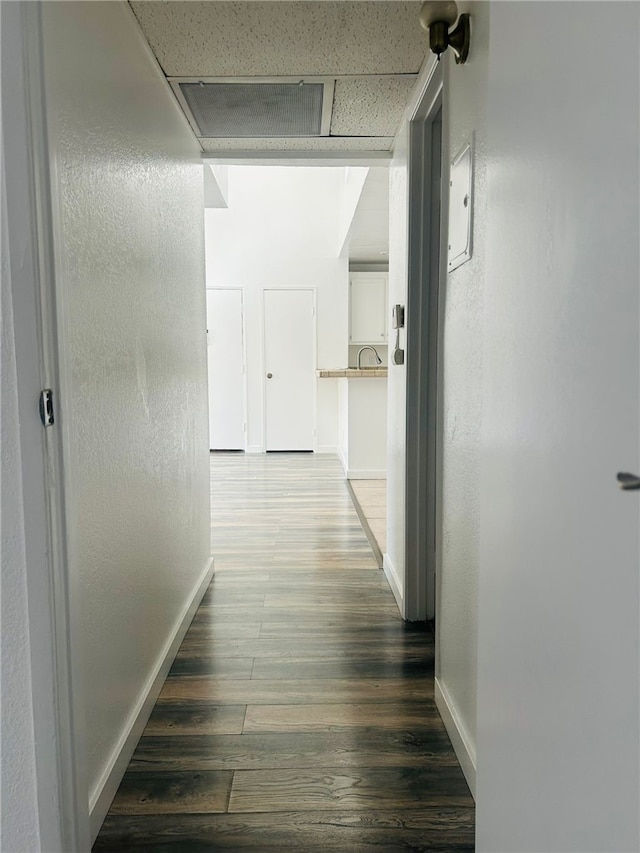 hallway featuring dark wood-type flooring and baseboards