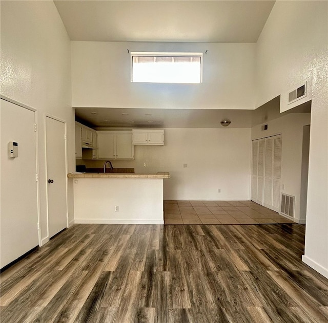 interior space with dark wood-style floors, visible vents, and a towering ceiling