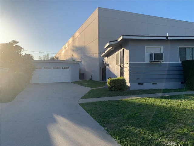 view of front of home featuring a wall unit AC, a detached garage, crawl space, stucco siding, and a front yard