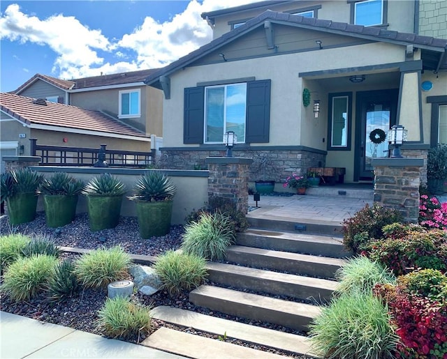 property entrance with stone siding, covered porch, and stucco siding