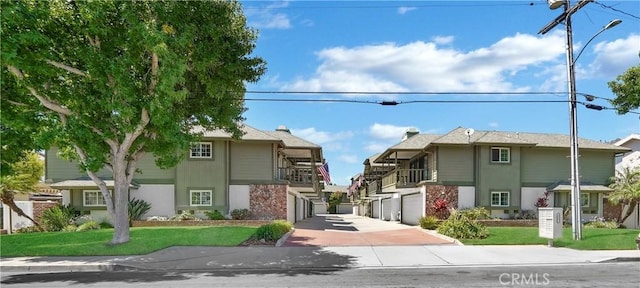 view of front of property with a balcony, a garage, stairs, driveway, and a front lawn