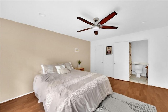 bedroom featuring ceiling fan, connected bathroom, baseboards, and wood finished floors