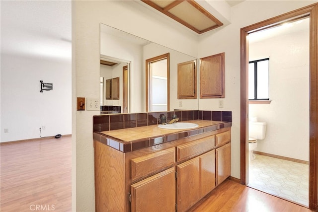 bathroom with baseboards, vanity, toilet, and wood finished floors