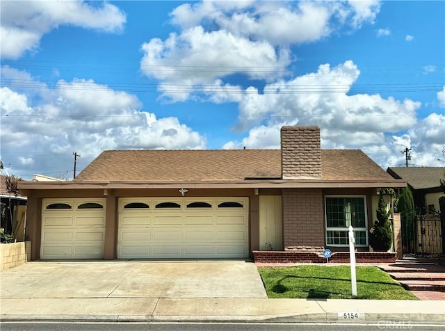 single story home with concrete driveway, an attached garage, and roof with shingles