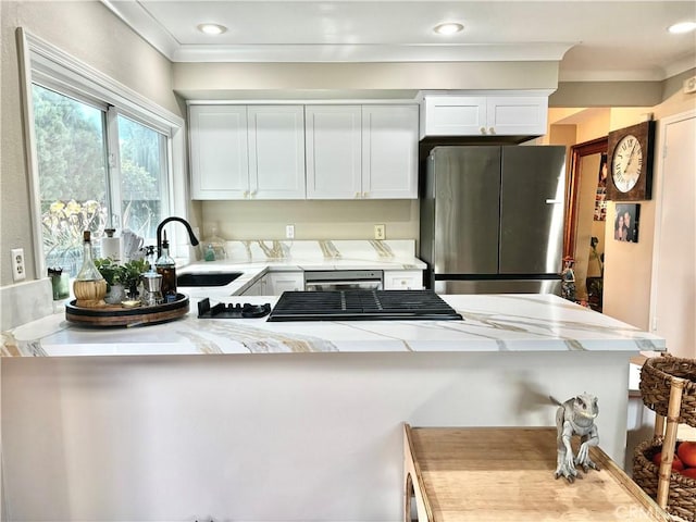 kitchen featuring a sink, white cabinetry, ornamental molding, and freestanding refrigerator