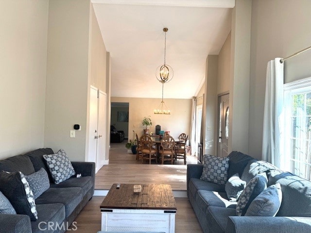 living room with a chandelier, high vaulted ceiling, and wood finished floors