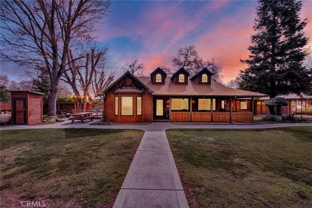 view of front of home featuring a patio, covered porch, a shed, an outdoor structure, and a front lawn