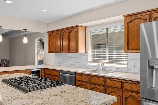 kitchen with appliances with stainless steel finishes, brown cabinetry, and a sink