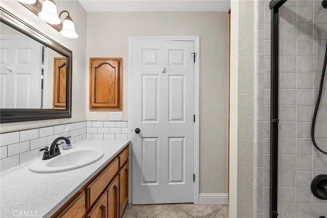 bathroom featuring a tile shower, backsplash, tile patterned flooring, and vanity