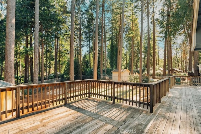 deck with an outdoor structure, fence, and a storage unit