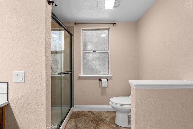 bathroom with toilet, a stall shower, visible vents, and baseboards