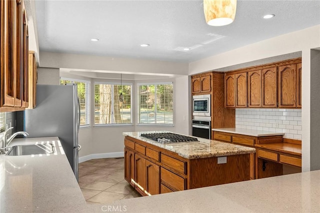 kitchen with brown cabinets, stainless steel appliances, tasteful backsplash, light tile patterned flooring, and a sink