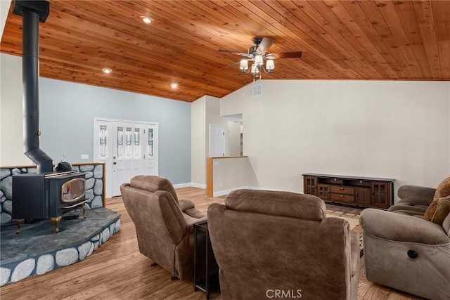 living room with visible vents, a wood stove, vaulted ceiling, wood finished floors, and wooden ceiling