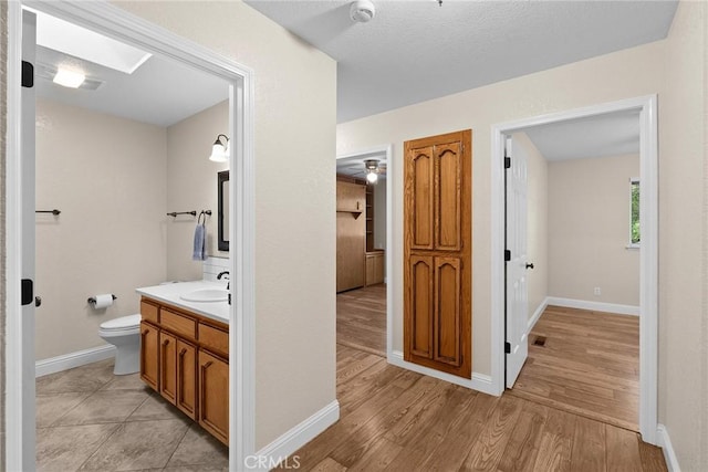 bathroom with wood finished floors, vanity, toilet, and baseboards