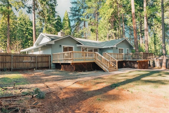 rear view of house with a chimney, fence, and a wooden deck