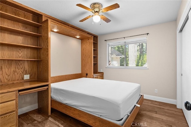 bedroom featuring dark wood-style flooring, built in desk, and baseboards