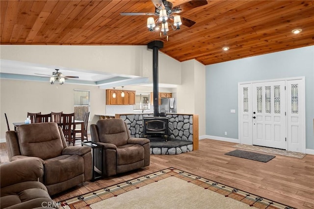 living room with baseboards, lofted ceiling, wooden ceiling, wood finished floors, and a wood stove