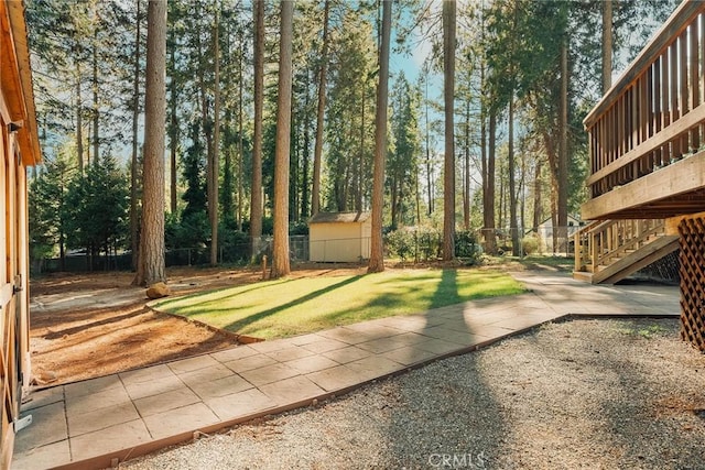 view of yard featuring an outbuilding, a storage shed, stairway, and fence