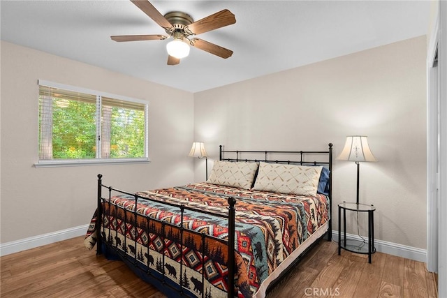 bedroom with ceiling fan, baseboards, and wood finished floors