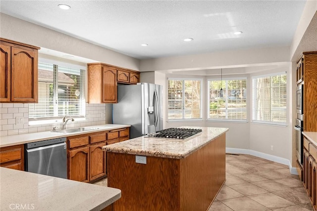 kitchen with stainless steel appliances, a sink, decorative backsplash, a center island, and brown cabinetry