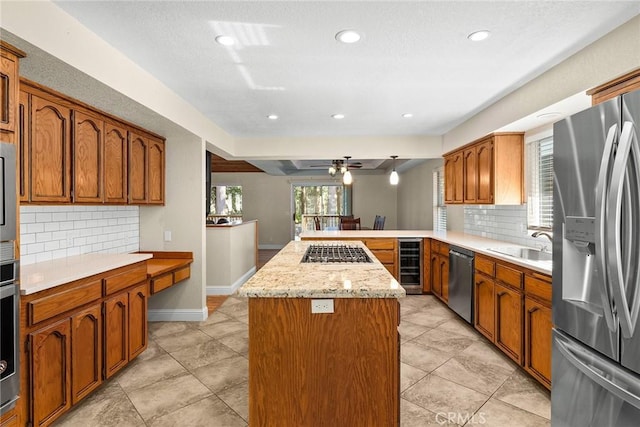 kitchen with beverage cooler, brown cabinetry, appliances with stainless steel finishes, a peninsula, and a sink