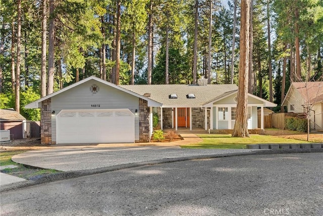 view of front of property featuring a chimney, an attached garage, fence, stone siding, and driveway