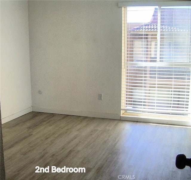 spare room featuring baseboards and wood finished floors