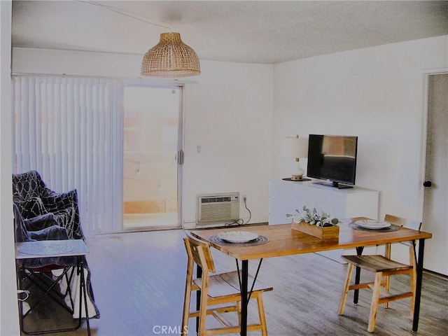 dining area with a wall unit AC, a textured ceiling, and wood finished floors