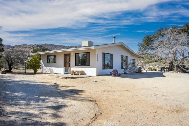 view of front facade with fence, a mountain view, and stucco siding