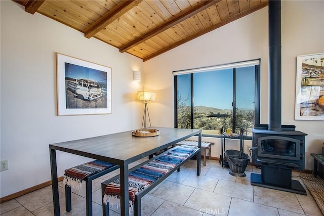 7716 Sunset Rd, Joshua Tree, CA 92252 - dining space featuring lofted ceiling with beams, a wood stove, baseboards, wooden ceiling, and light tile patterned floors