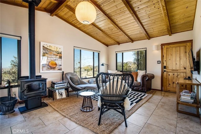 dining space with beamed ceiling, wood ceiling, light tile patterned floors, a wood stove, and high vaulted ceiling