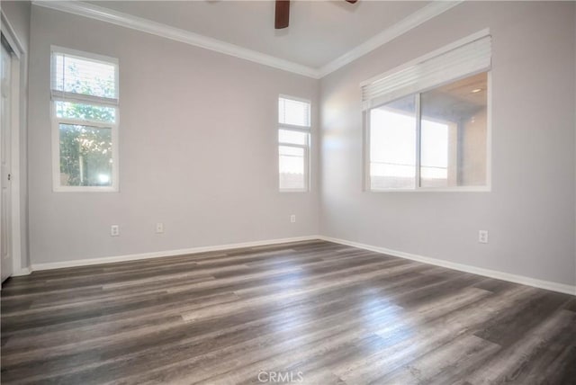 empty room with ornamental molding, dark wood-style flooring, a healthy amount of sunlight, and baseboards