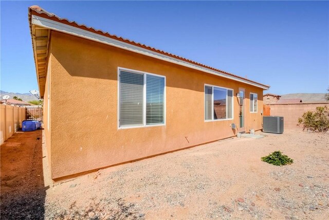 view of side of home featuring central AC, a fenced backyard, and stucco siding